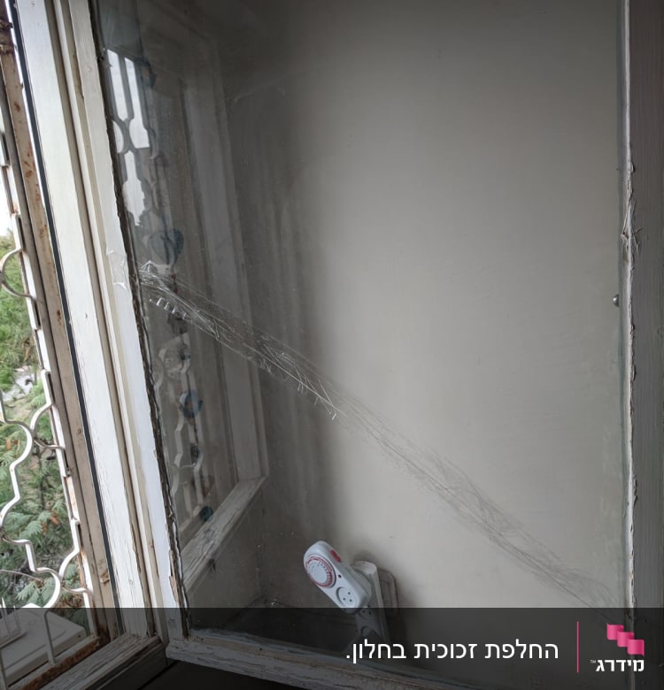 זכוכית עם סדקים בתוך מסגרת חלון ישנה